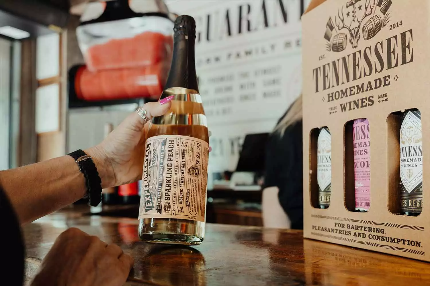 A person holding a bottle of Tennessee Homemade wine.